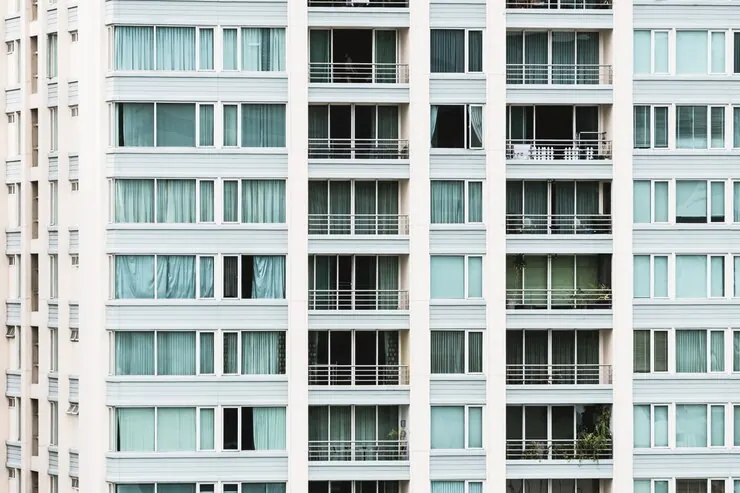 The front of a tall block of flats, with balconies and large windows on every floor